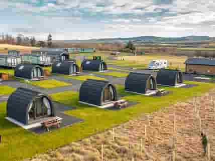 Camping pods with touring and camping pitches in the background