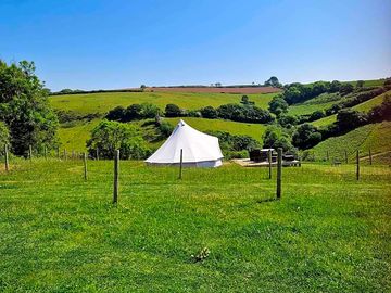 Bell tent surrounded by sloping countryside