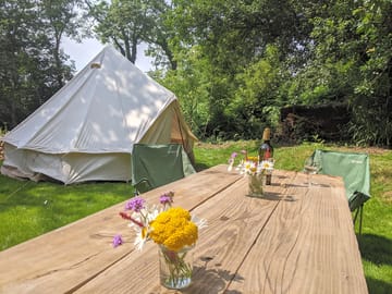 Bell tent and picnic table set with wild flowers from the wood
