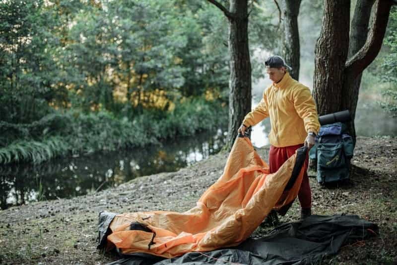 A man laying his tent down (Thirdman / Pexels)
