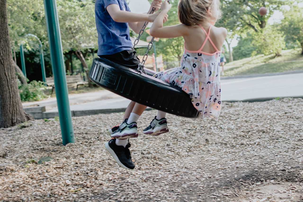 Kids on a tyre swing at a playground (Kelly Sikkema on Unsplash)