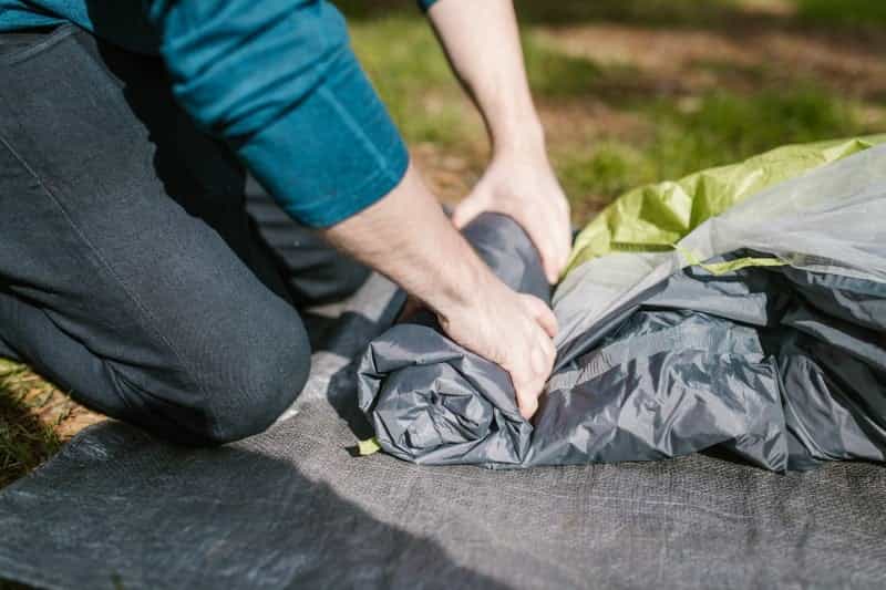A man rolls up a tent (RODNAE / Pexels)