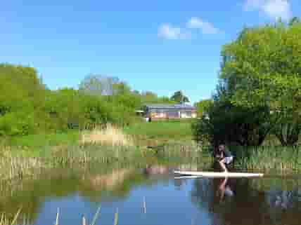 Taking a paddle board out on the wildlife pond, Balebarn Eco Lodge in the background