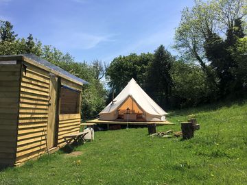 The bell tent kitchen and firepit on a sunny day