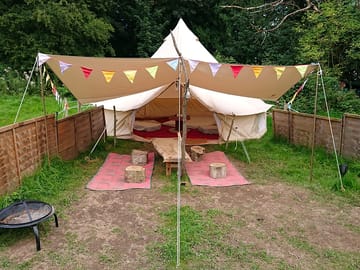 Bell tent with awning, fencing, fairy lights, firepit and low tables